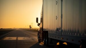a commercial truck driving on a highway at sunset