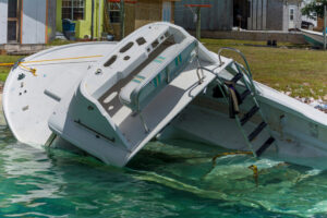 A partially sunk boat by the coastline of a harbor area