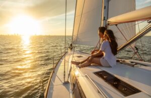 Fun adventures at sea for attractive young couple with luxury lifestyles relaxing on private yacht at sunrise